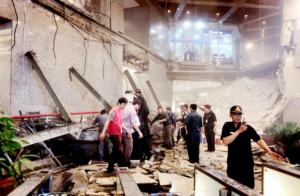 Indonesian security stand near the ruin of a structure inside the Jakarta Stock Exchange tower in Jakarta, Indonesia, Monday, Jan. 15, 2018. A structure inside the Jakarta Stock Exchange tower collapsed Monday, injuring at least several people and forcing a chaotic evacuation. (AP Photo) --- Foto: AP