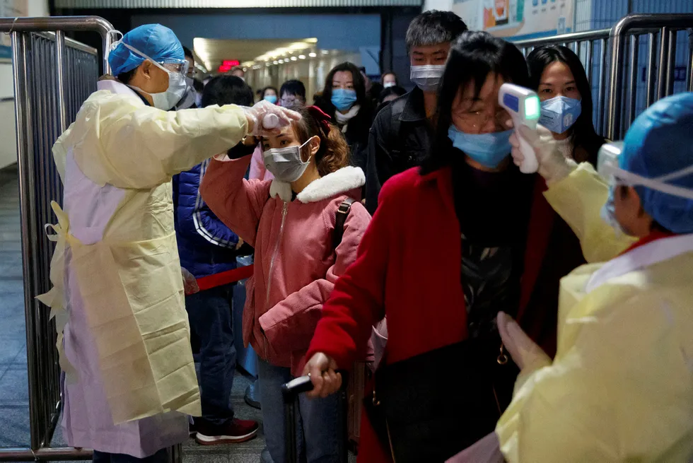 Weighing on oil prices: medical workers take the temperature of passengers after they got off the train in Jiujiang, Jiangxi province, China, as the country is hit by an outbreak of a new coronavirus