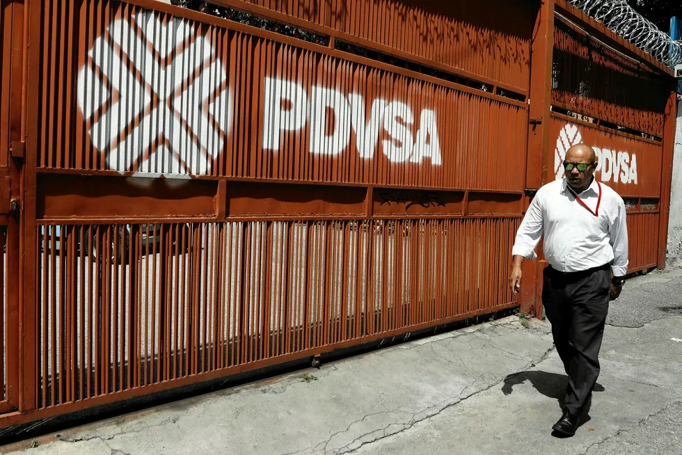 Sign of the times: a man walks past a gate with the PDVSA corporate logo in Caracas