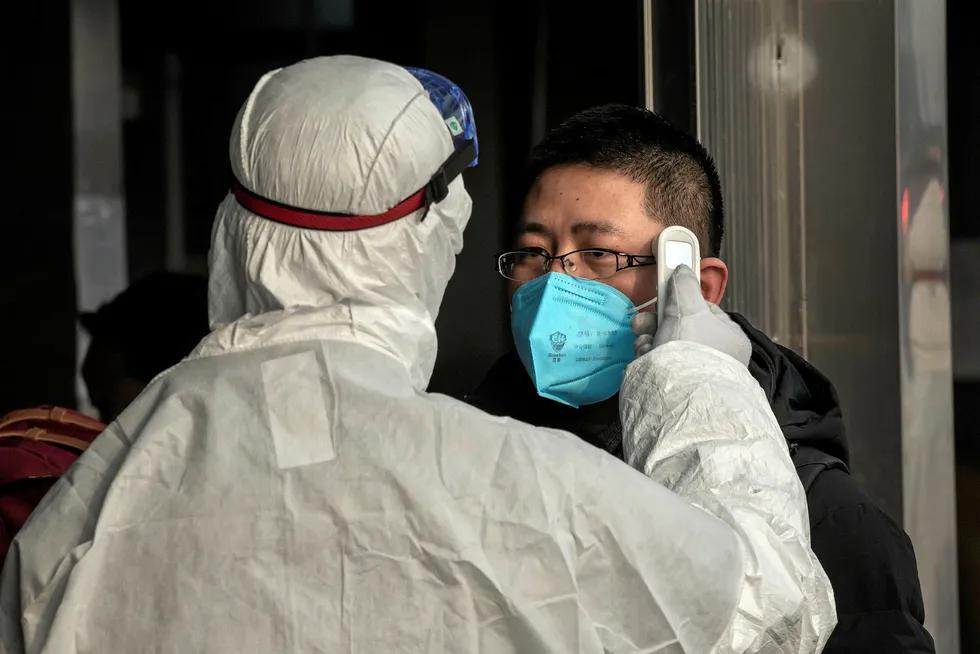 Protective measures: a security guard wearing protective clothing checks the temperature of a man at a subway station entrance in Beijing this week as China steps up action to deal with the coronavirus outbreak