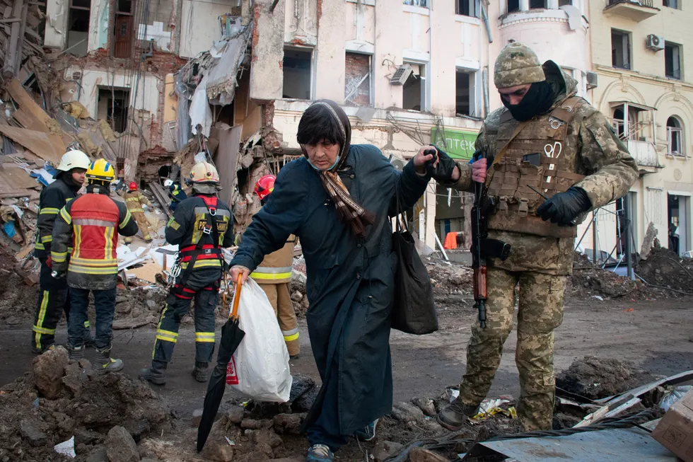 En kvinne får hjelp av en mann fra den ukrainske forsvarsstyrken i en gate i Kyiv.