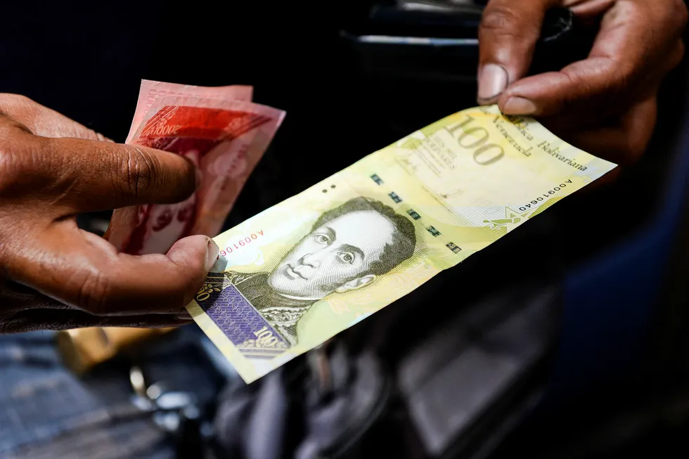 Venezuela vil trolig havne i mislighold av landets enorme statsgjeld. På bildet viser en mann frem landets nye 100.000-Bolivar-seddel. i det offisielle markedet er den verdt 29,89 dollar, men på svartebørs kan man kjøpe den for to dollar. Foto: Federico Parra