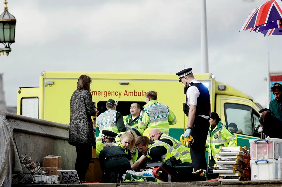 En skadet person på Westminster-broen får hjelp etter hendelsen. Vitner har forklart til britiske medier at de så en bil meie ned flere personer på broen. Foto: Matt Dunham/AP/NTB scanpix