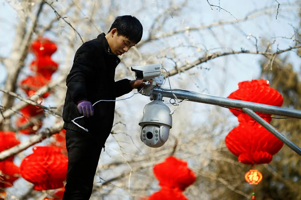 En arbeider setter opp overvåkningskameraer fra Hikvision i Beijing i anledning av den kinesiske nyttårsfeiringen i februar. Artikkelforfatterne bruker Oljefondets investering i Hikvision som et eksempel på de vanskelige etiske dilemmaene fondet står overfor.