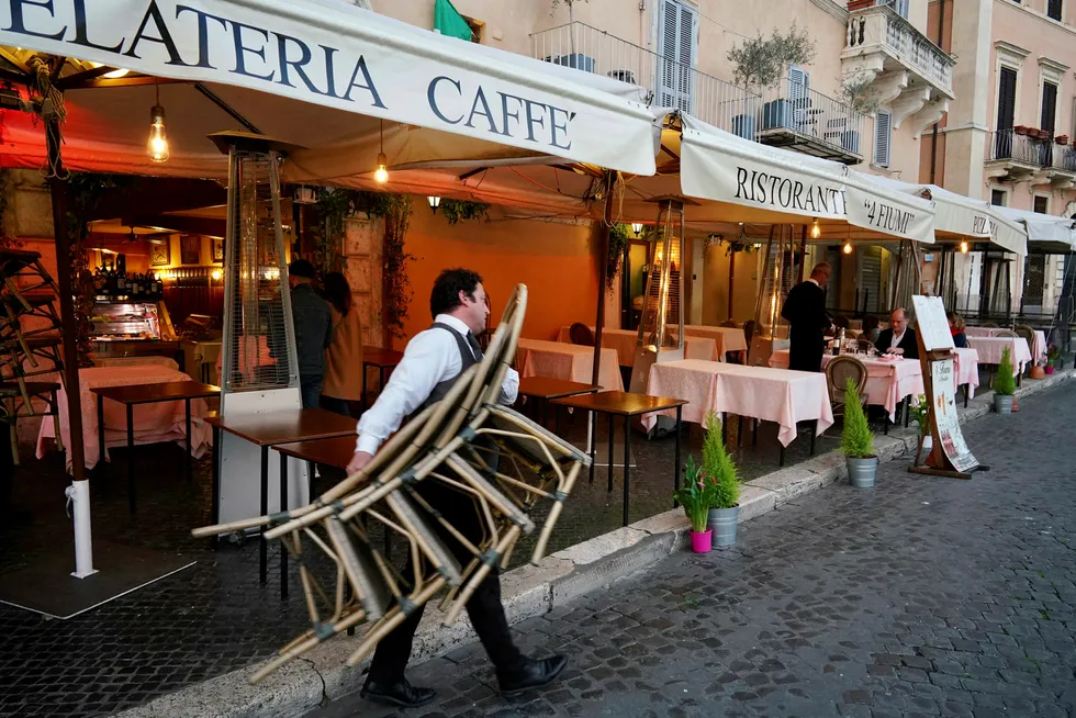 Kelnere tar inn stoler og bord når en restaurant i Roma må stenge klokken 18 på grunn av koronaviruset.