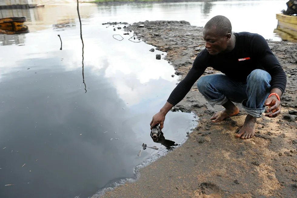 Complex issue: a man scoops spilled crude into a bottle in Nigeria's Niger Delta