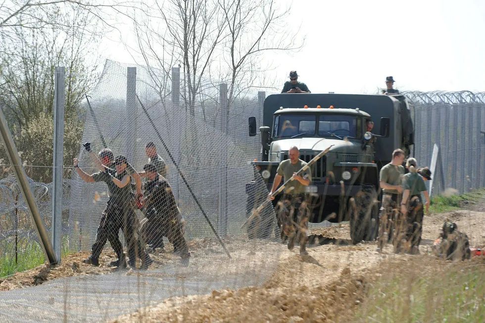 Arkivfoto fra april i fjor viser ungarske soldater i ferd med å sette opp et gjerde langs grensen mot Serbia. Nå er et nytt grensegjerde i ferd med å bygges. Foto: Foto: AP / NTB scanpix