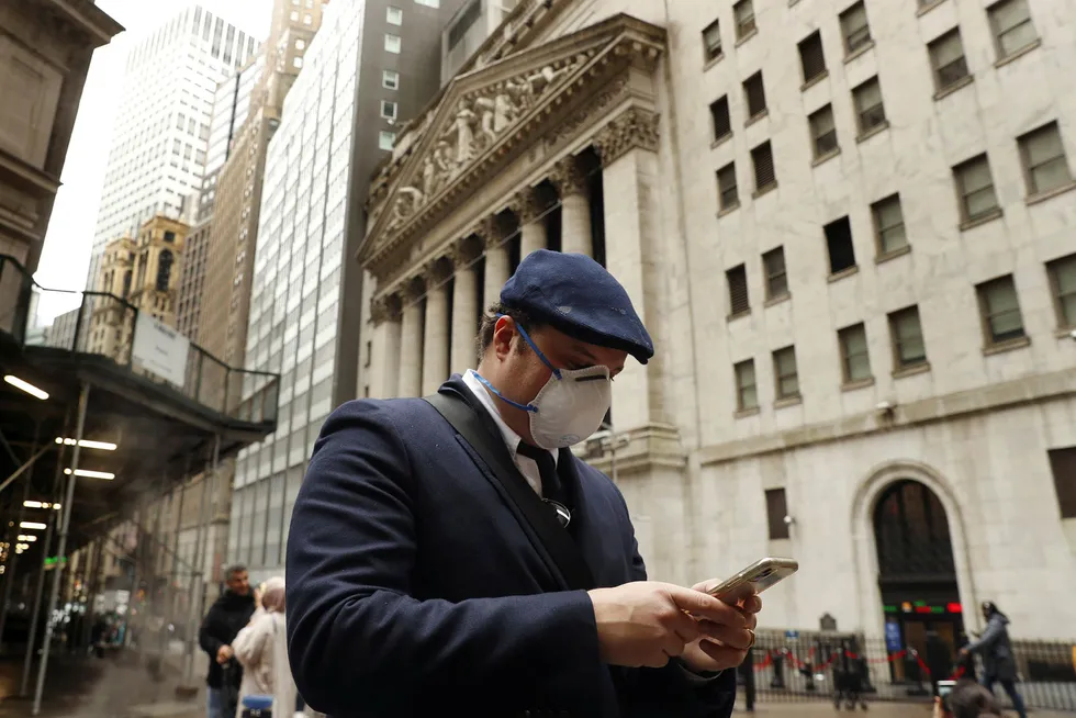 USA-børsene stiger videre onsdag. Bildet viser en mann med munnbind på Wall Street, nå er USA i ferd med å åpne opp landet igjen etter alle koronarestriksjonene.