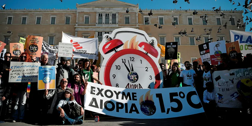 People hold banners and a mock clock reading "we have 1.5 (Celsius degrees) time" during a protest in front of the Greek parliament in Athens calling for action against climate change.