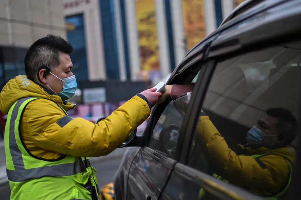 Infection fears: a guard checks the temperature of customers to give access to the parking area of a shopping mall in Wuhan, China