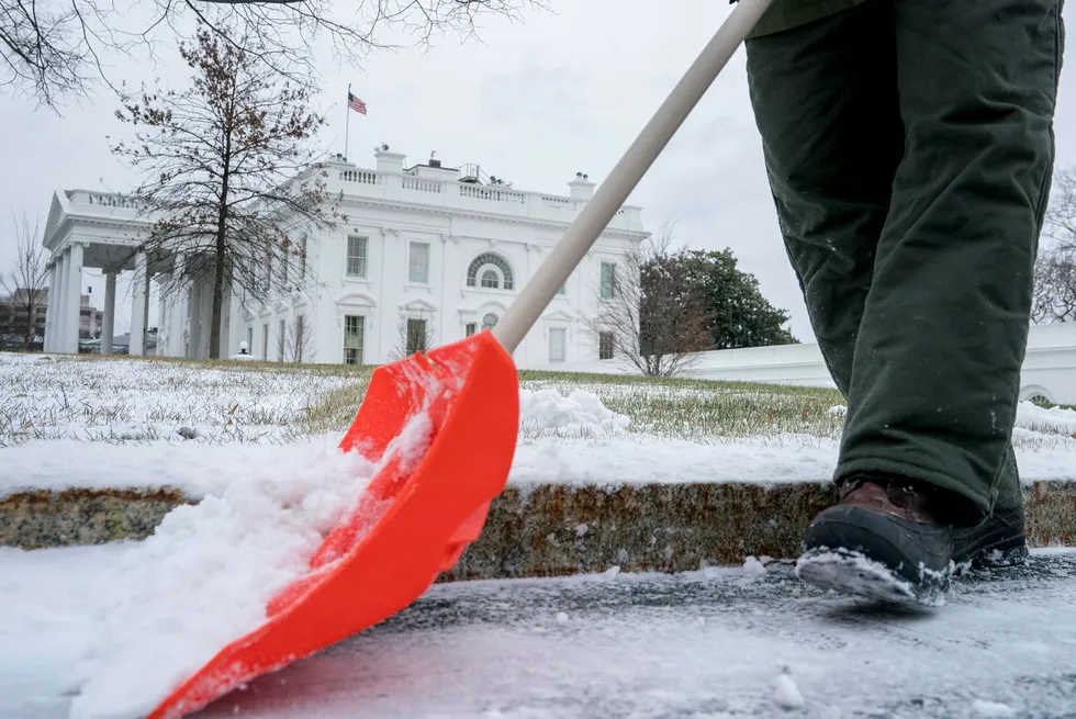 En ansatt i National Park Service skuffer vekk snø utenfor Det hvite hus i Washington, D.C. i USA torsdag. Foto: Andrew Harnik / AP / NTB Scanpix