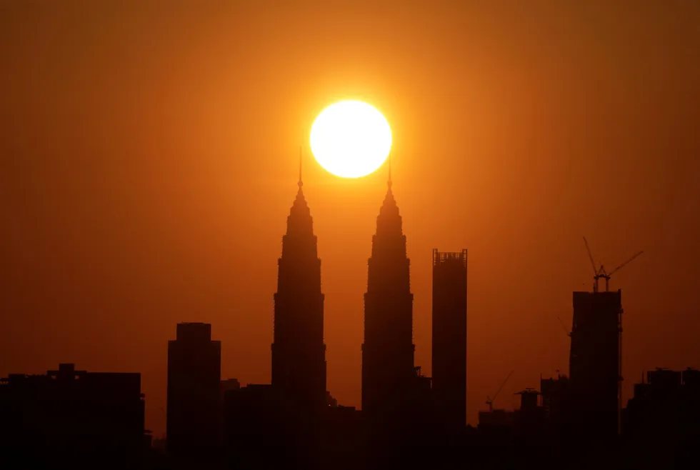The sun sets behind the Petronas Twin Towers in Kuala Lumpur, Malaysia