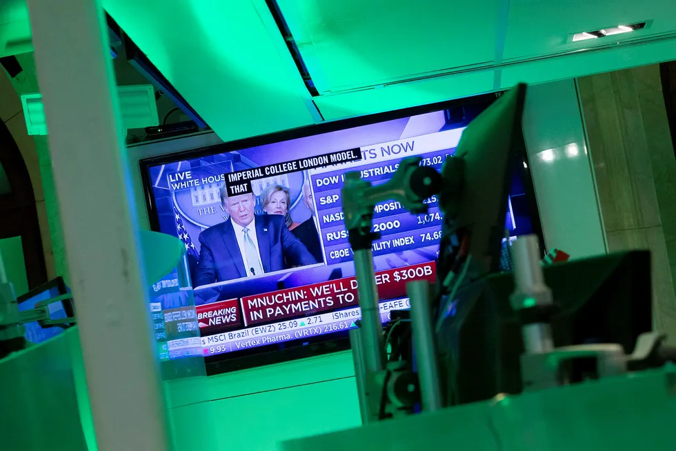 Donald Trumps pressekonferanse overværes på en skjerm på New York Stock Exchange, som holder til på Wall Street. Presidentens løfter om krisetiltak bidro til at indeksene steg tirsdag.