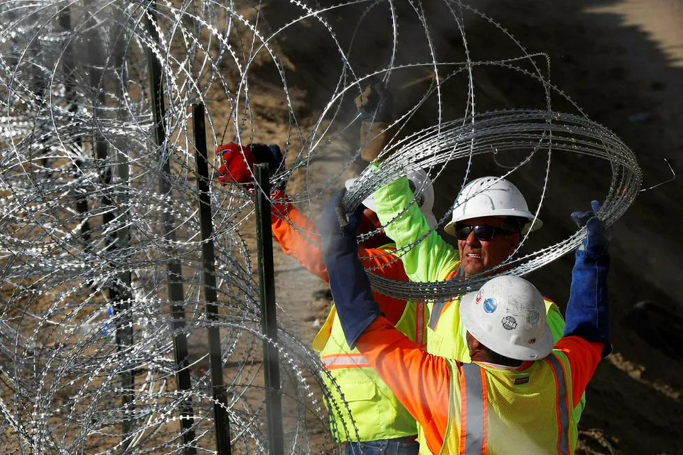 Arbeidere legger piggtråd langs grensen mellom USA og Mexico.