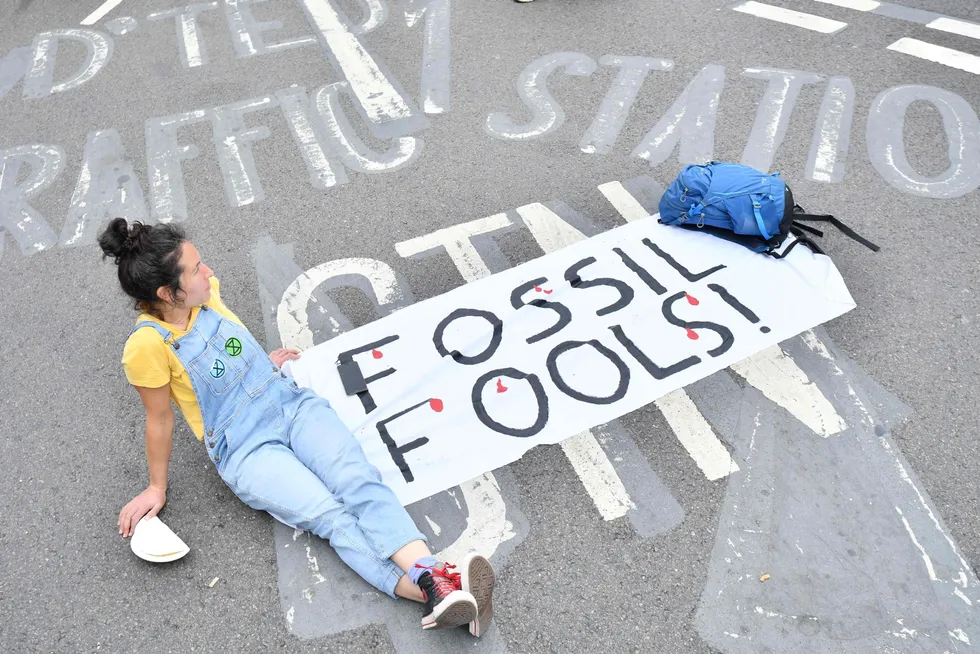 Sit down protest: a climate activist from the Extinction Rebellion group sits in the street with an anti-fossil fuel message blocking London Bridge in central London