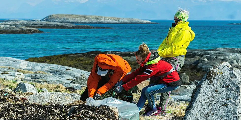 Tre medlemmer av Bodø Seilforening i ferd med å fjerne tauverk fra en trålpose som er grodd ned i tanget.