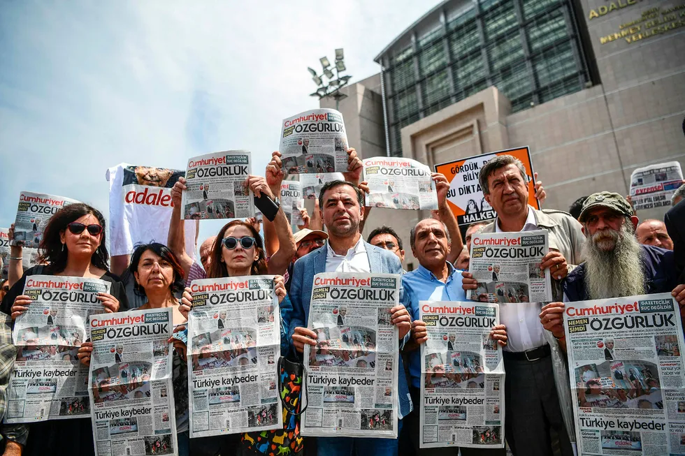 Folk holder opp dagens utgave av Cumhuriyet i protest, fredag 28. juli, utenfor domstolen der saken mot journalister fra avisen føres. Foto: OZAN KOSE