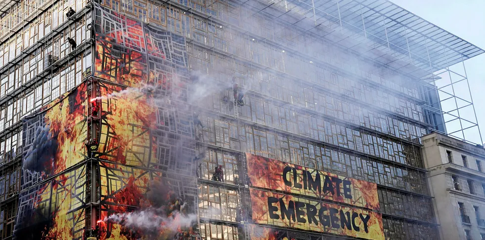 Activists of the environmental NGO Greenpeace hold flares after attaching a giant banner on the frontage of European Council's building in Brussels during a protest action in Brussels, on December 12, 2019 ahead of the European Summit