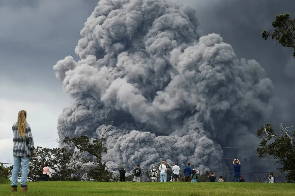 HAWAII VOLCANOES NATIONAL PARK, HI - MAY 15: People watch at a golf course as an ash plume rises in the distance from the Kilauea volcano on Hawaii's Big Island on May 15, 2018 in Hawaii Volcanoes National Park, Hawaii. The U.S. Geological Survey said a recent lowering of the lava lake at the volcano's Halemaumau crater 'has raised the potential for explosive eruptions' at the volcano. Mario Tama/Getty Images/AFP== FOR NEWSPAPERS, INTERNET, TELCOS Foto: MARIO TAMA