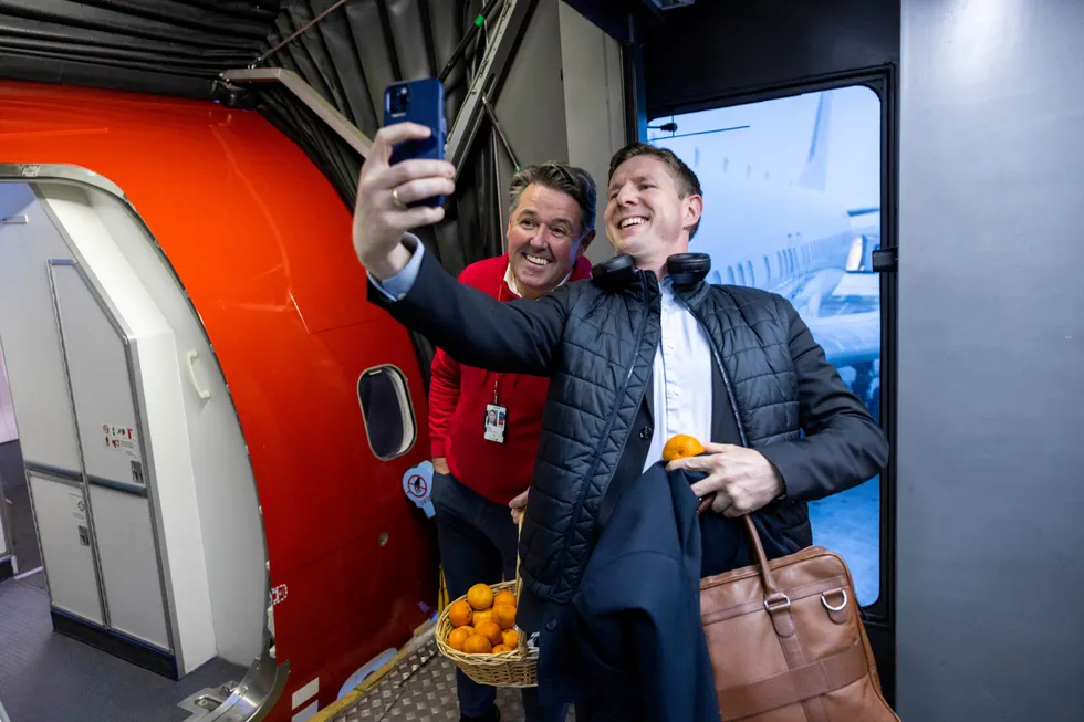 Norwegian-sjef Geir Karlsen (fra venstre) var tidligere i uken på Gardermoen for å ønske passasjerer og ansatte god jul. Passasjer Ølver Haveland var først ombord i 15.30-flyet til Bergen og benyttet anledningen til å få en klementin og en selfie.