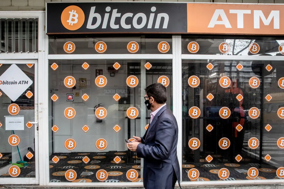 Prisen på bitcoin faller fredag. Her passerer en fotgjenger en bitcoin-minibankkiosk i Barcelona i Spania.