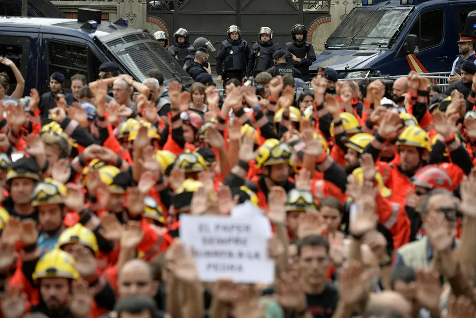 Brannmenn løfter nevene i protest mot politiets fremferd i forbindelse med søndagens folkeavstemning. Store deler av Barcelona ble lammet under tirsdagens generalstreik. Foto: Joseph Lago, AFP/NTB Scanpix