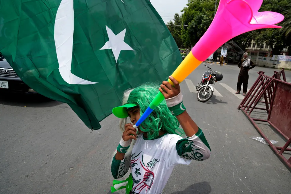 Celebration: a youngster plays bugle next to a national flag to celebrate Pakistan's Independence Day in Lahore, Pakistan.