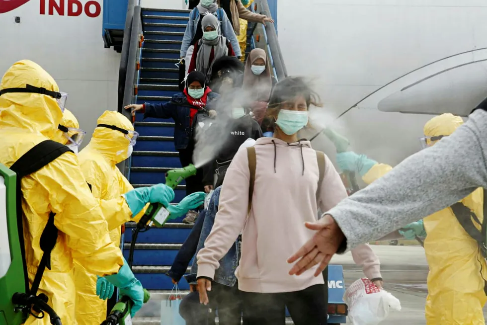 Indonesisk statsborger blir sprayet med antiseptisk middel etter å ha kommet med fly fra Kina.