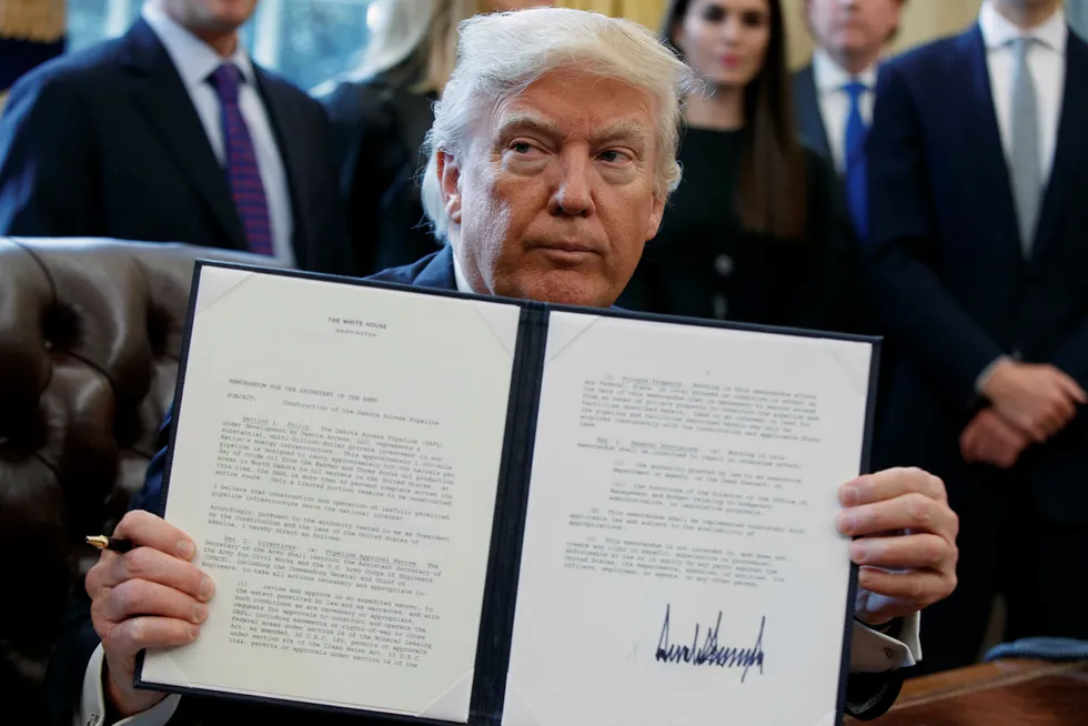 President Donald Trump holder opp et undertegnet dokument om rørledningen som skal bygges i Dakota. Foto: AP Photo/Evan Vucci
