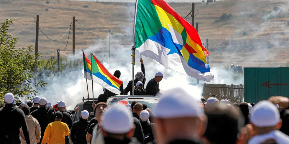 Tear gas fumes fill the air as members of the Druze community gather with their flags in a protest against an Israeli wind project.