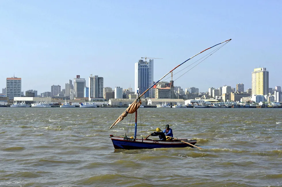 Traditional fishing boats sail beneath Maputo's skyline, in Mozambique