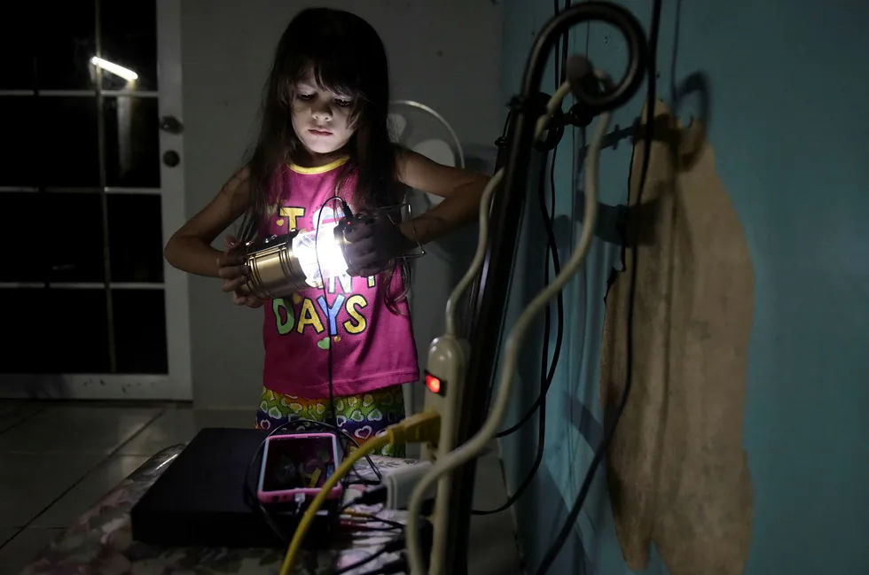 Seks år gamle Melanie Oliveras Gonzalez holder en lanterne inne i stuen der hun og familien bor i Morovis i Puerto Rico. Halvparten av landets strømkunder er fortsatt uten strøm, tre måneder etter at orkanen Maria traff øya. Foto: Carlos Giusti / AP / NTB scanpix