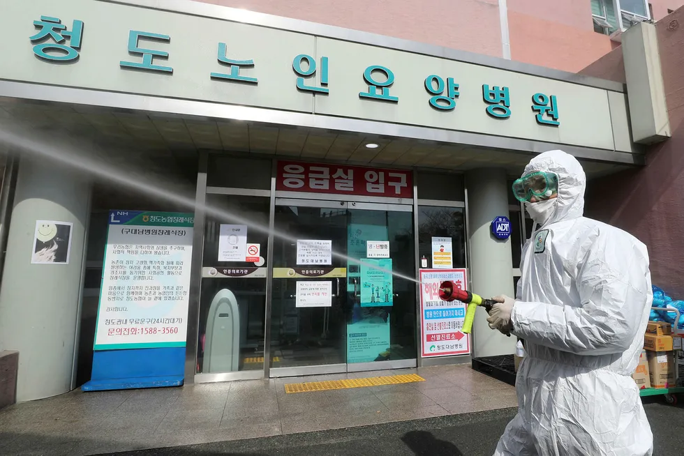 Spreading virus: a worker wearing protective gear sprays disinfectant against the coronavirus in front of the Daenam Hospital in Cheongdo, South Korea