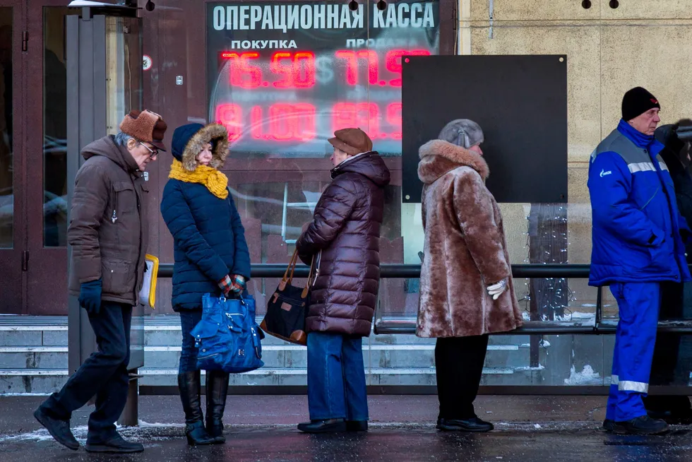 Den russiske økonomien kommer til å gå inn i en resesjon, ifølge valutastrateg Magne Østnor. Her står mennesker og venter på bussen foran en valutaveksler i Russlands hovedstad Moskva.