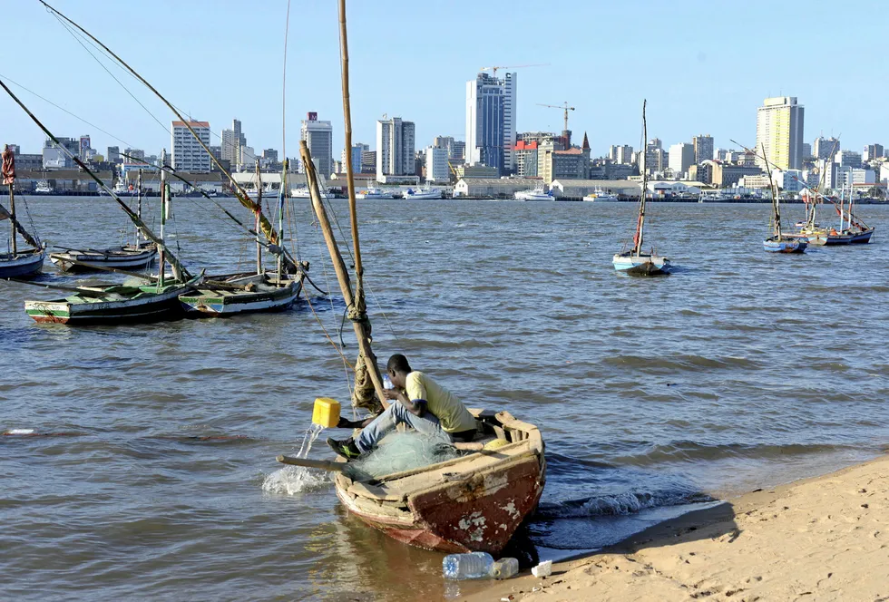 Major catch: a fisherman cleans his boat beneath Maputo's skyline