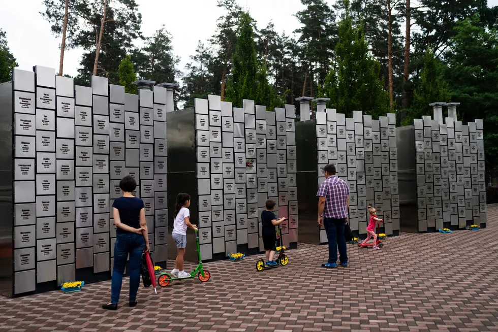 En ukrainsk familie besøker en minnevegg for alle drepte som russiske styrker sto bak i Butsja.