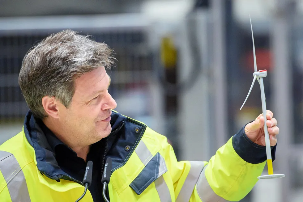 Robert Habeck holding a model wind turbine while visiting a Siemens Gamesa wind turbine factory.