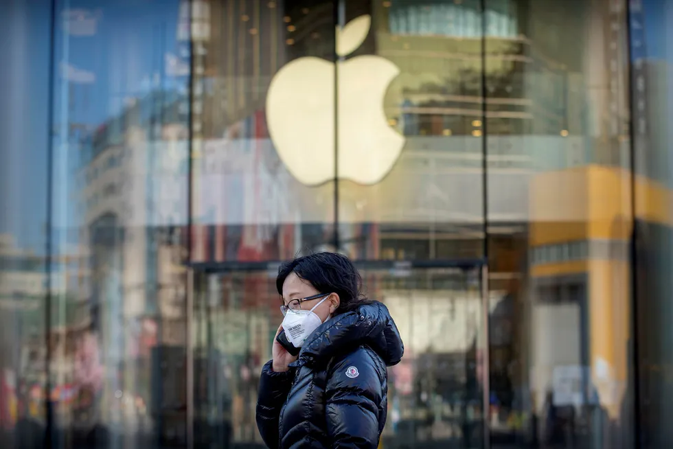 En kvinne med ansiktsmaske passerer en av Beijings Apple-butikker. De er midlertidig stengt på grunn av virusutbruddet.