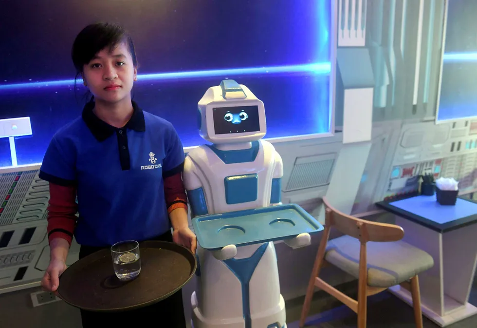 To av servitørene ved Hanois nyåpnede Robo Cafe. Til høyre er roboten «Mortar» klar til å servere kundene drikkevarer og snacks, og beveger seg over gulvet ved hjelp av elektromagnetiske sensorer. Foto: Hoang Dinh Nam/AFP/NTB Scanpix