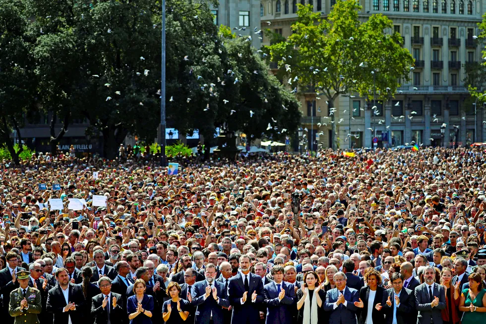 Kong Felipe av Spania (i midten av bildet foran) og statsminister Mariano Rajoy (til venstre for kongen) holdt ett minutts stillhet mens duene fløy over Placa de Catalunya i Barcelona, dagen etter at terroren drepte 14 mennesker i paradegaten La Rambla. Foto: Susana Vera/Reuters/NTB Scanpix