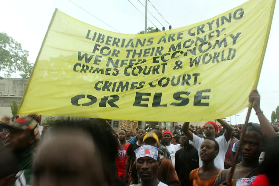 Liberiske demonstranter holder et banner i en demonstrasjon i hovedstaden Monrovia mandag.