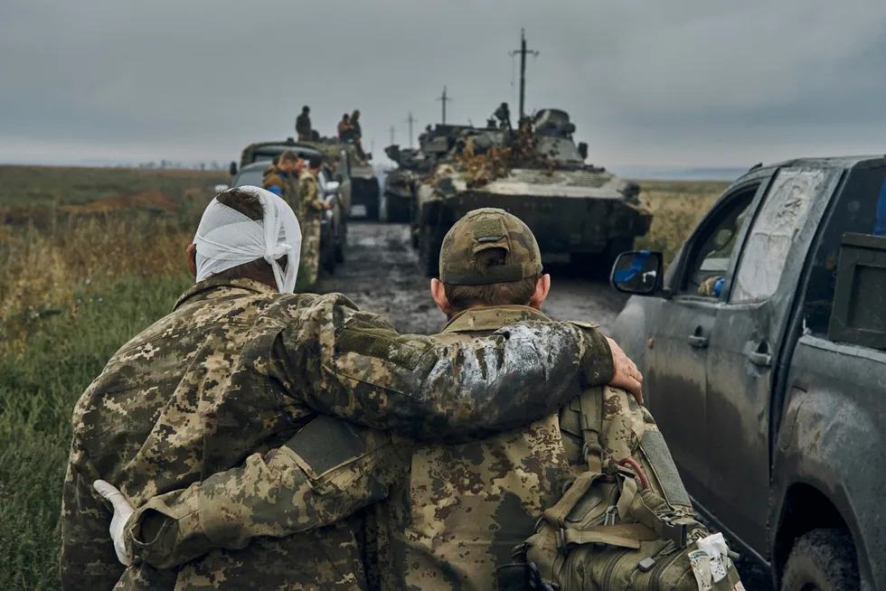 En ukrainsk soldat hjelper en såret medsoldat i det frigjorte området i Kharkiv-regionen.