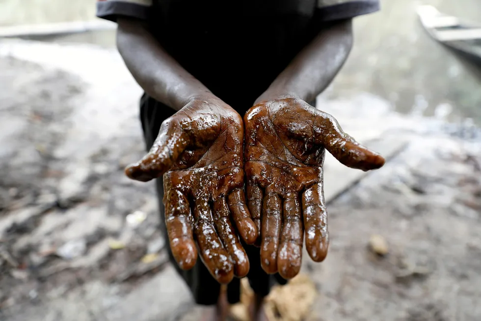Aftermath: a woman shows her hands stained by oil following an oil spill in Nigeria