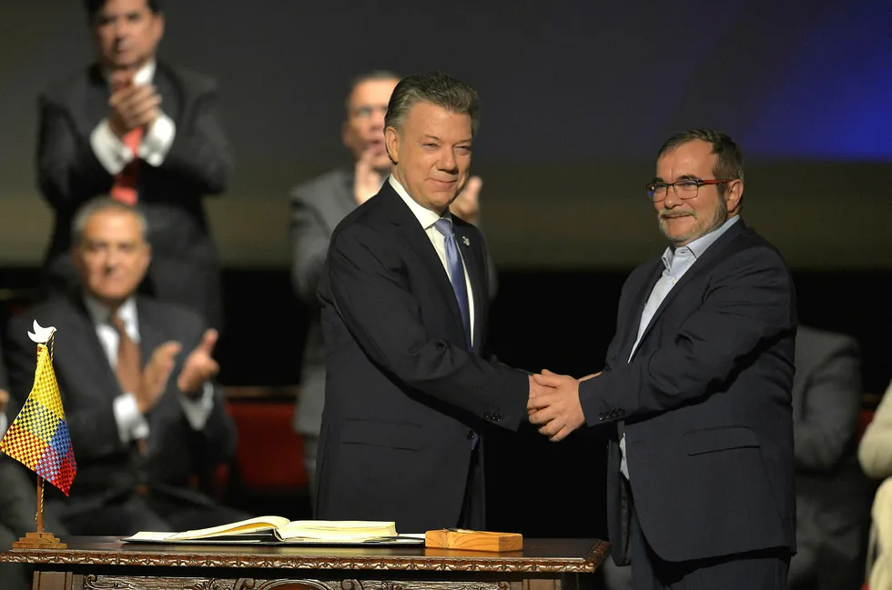 Colombias president Juan Manuel Santos (til venster) og leder av Farc-gerilliaen Timoleon Jimenez, også kjent som Timochenko, håndhilser etter den historiske fredsavtalen. Foto: Luis Robayo/AFP Photo/NTB scanpix