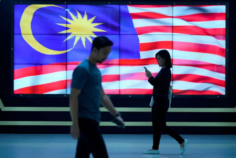 Downtown Kuala Lumpur: pedestrians walk past an election board displaying the national flag in the Malaysian capital city.