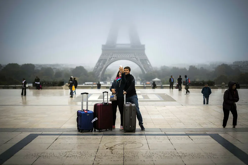 Turister i Paris tar en selfie med Eiffeltårnet i bakgrunnen.