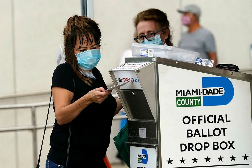 Valgmedarbeidere legger postsendte stemmesedler inn en mottakskasse i Miami. Med en knapp uke igjen til valget har flere titall millioner amerikanere til gode å returnere de ferdig utfylte stemmesedlene sine