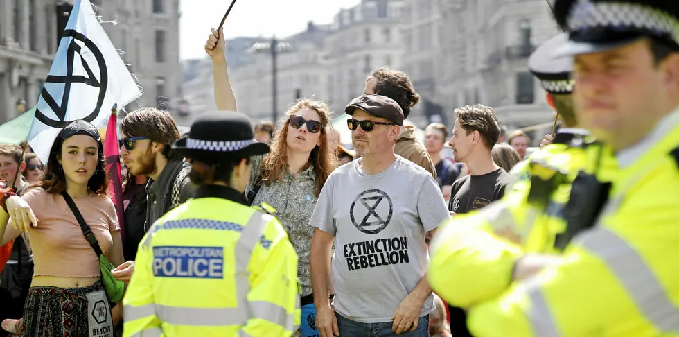 Police officers keep watch as climate change activists occupy the road junction at Oxford Circus in central London on April 19, 2019, the fifth day of an environmental protest by the Extinction Rebellion group.