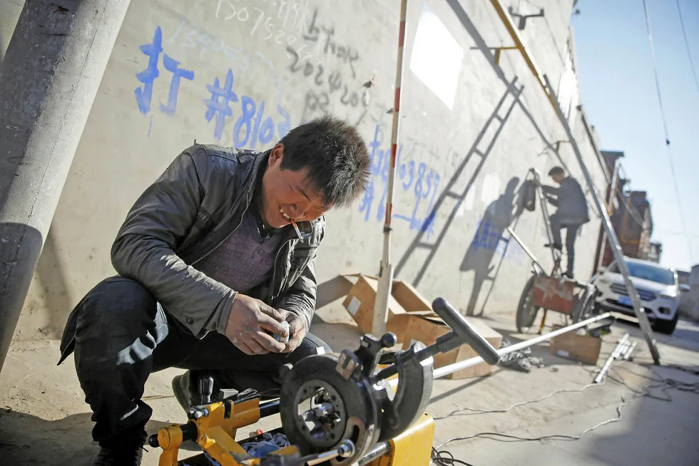 Fitting out: workers install gas pipes along the walls of residential houses in China's Hebei province