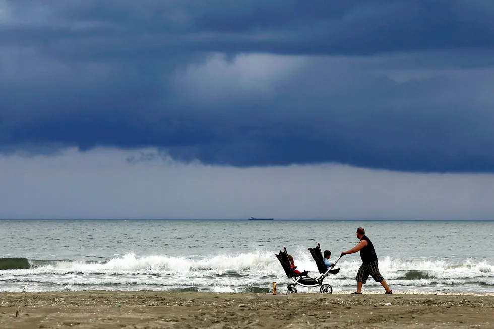 Stroller: a man pushes a pram on a beach by the Black Sea in Navodari, Romania
